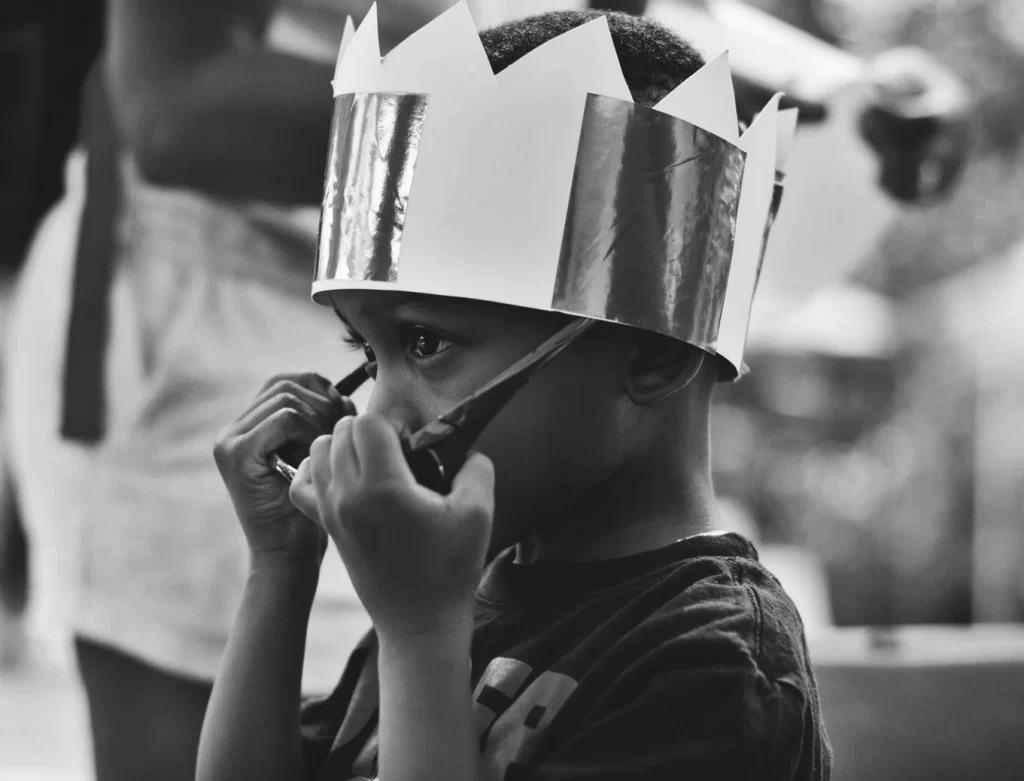A child in a hand-made paper crown.
